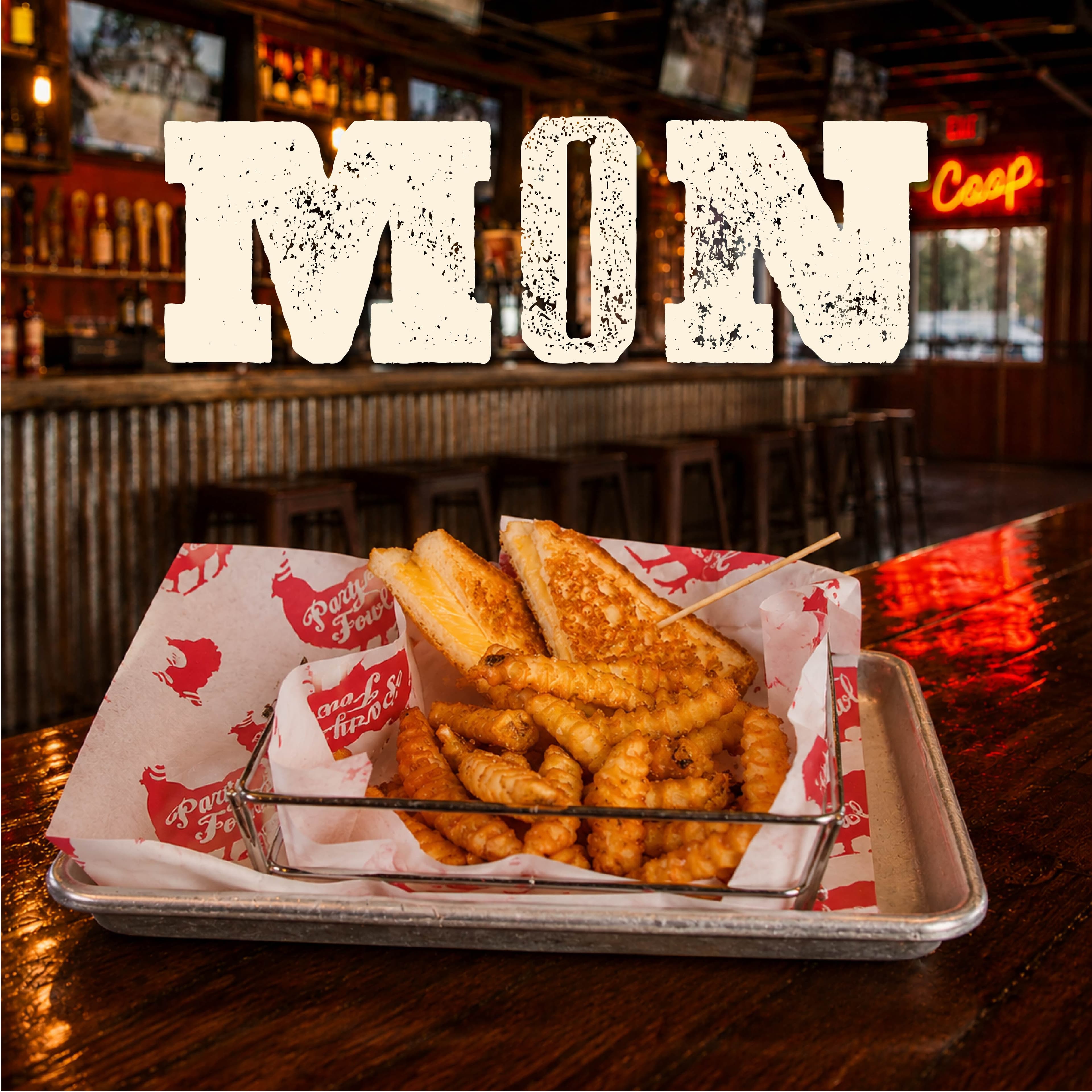 PF WeeklySpecials Image 01 A tray of crispy fries and a grilled sandwich with a toothpick, served in a branded basket at a bar setting.