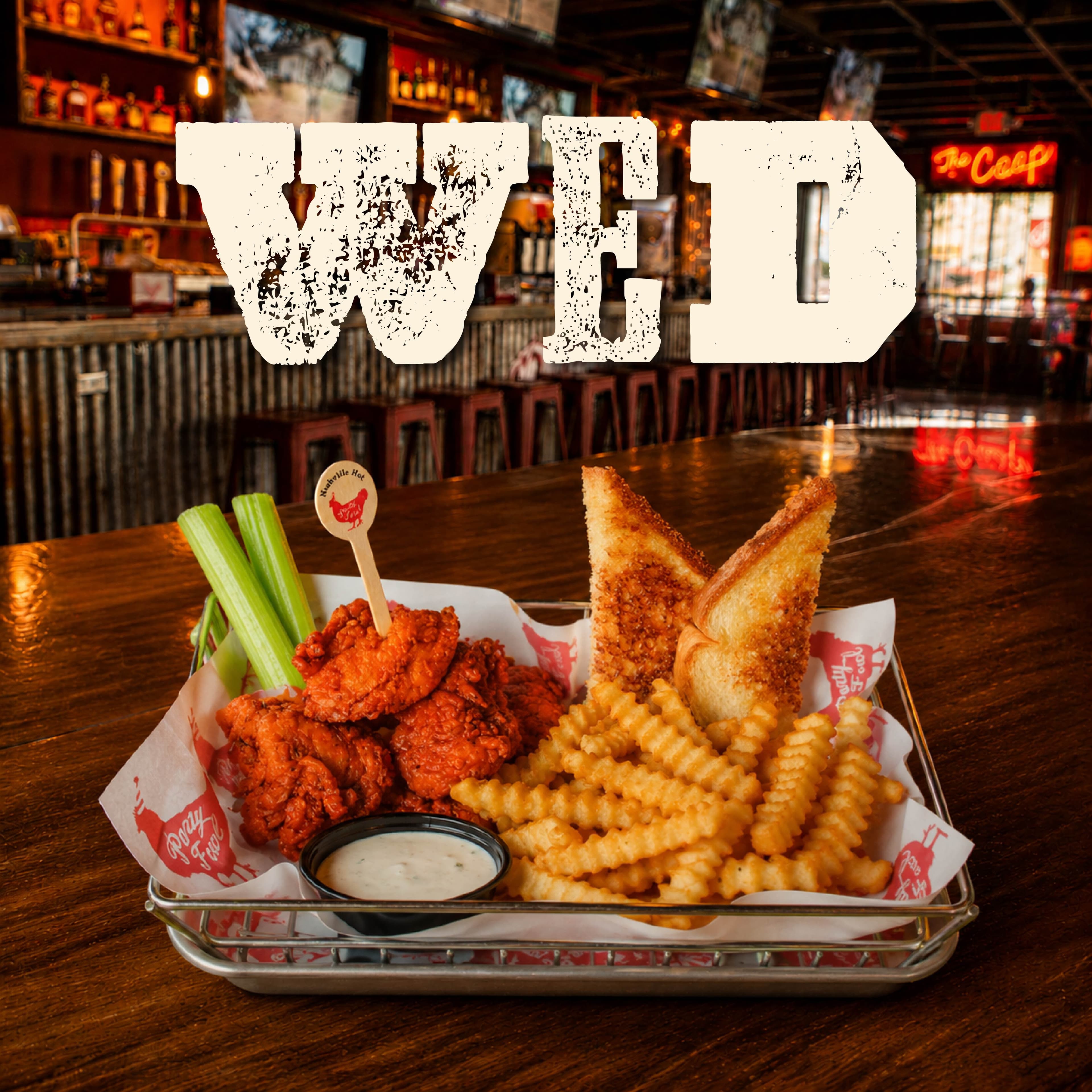 PF WeeklySpecials Image 03 A basket of crispy fried chicken, waffle fries, and garlic bread served with celery and ranch dressing in a bar setting.