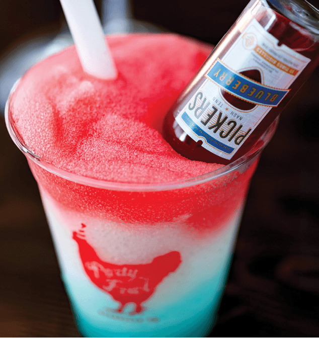 Boozy Slushies A vibrant, layered slushie with a blueberry liquor bottle and a straw, perfect for a refreshing adult treat.