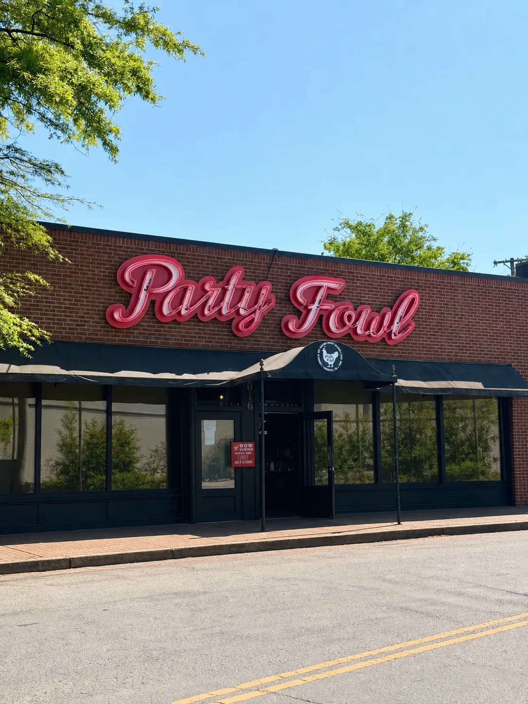 East Nashville Party Fowl Location A brick storefront with a large neon sign reading 'Party Fowl' under a clear blue sky.